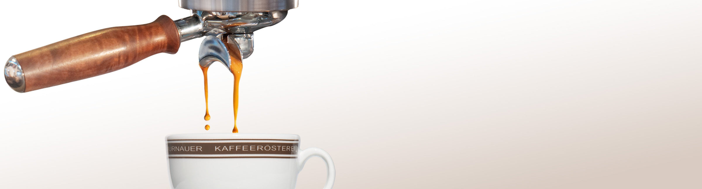 Siebträgermaschine lässt goldbraunen Espresso in eine Tasse der Murnauer Kaffeerösterei laufen, Tropfen fallen in die frische Crema, Henkel des Siebträger KI erweitert mit Firefly Image 3