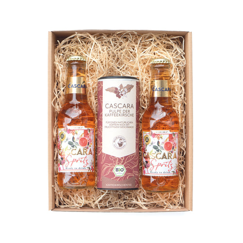 Geschenkset mit zwei Cascara Spritz Flaschen und Dose Cascara Kaffeekirschen-Tee im Karton mit Holzwolle, frontal