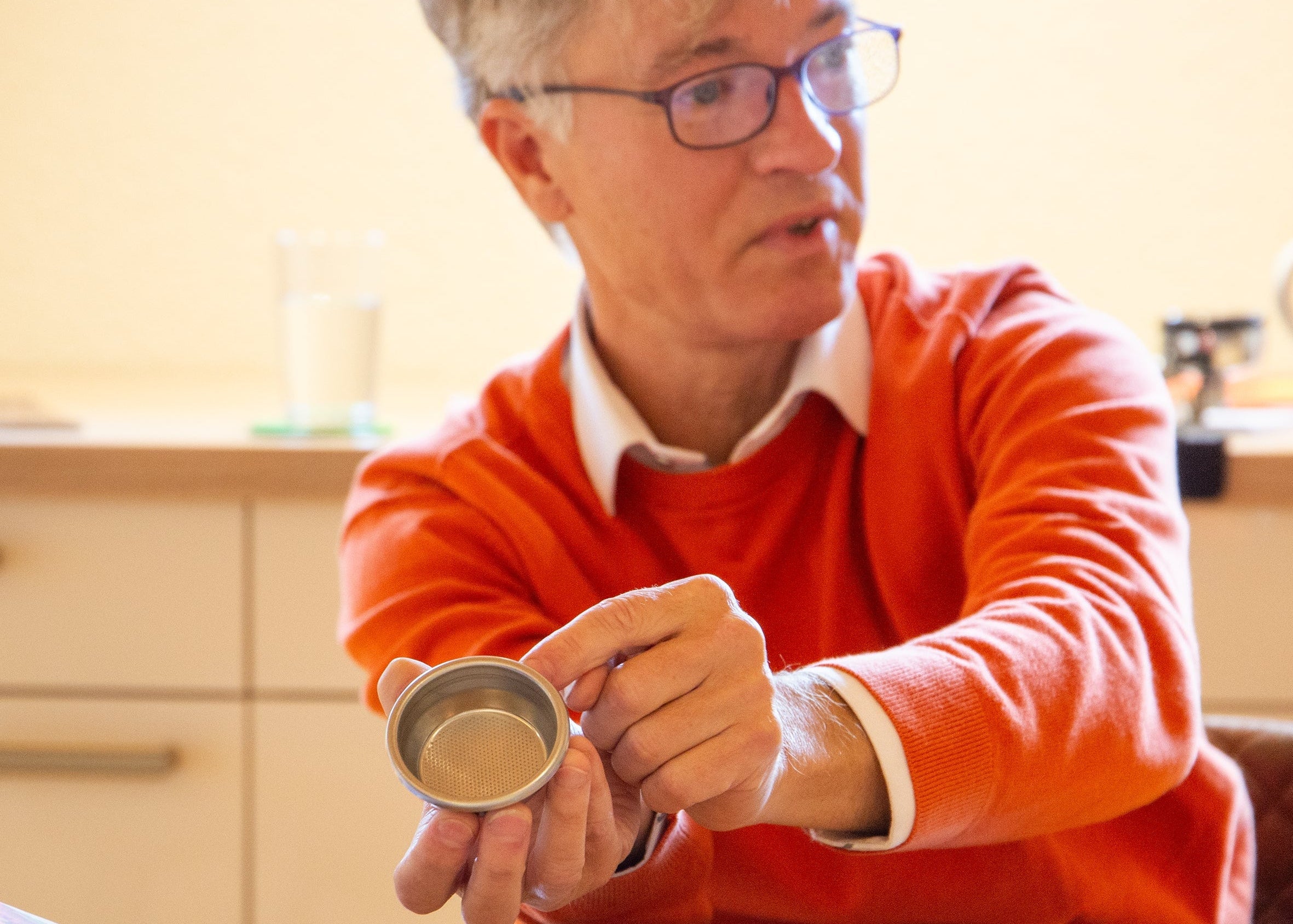 Barista Trainer zeigt Siebträger-Einsatz im Espresso Seminar der Murnauer Kaffeerösterei am Holztisch mit Zubehör, Baristakurs Espresso & Latte Art