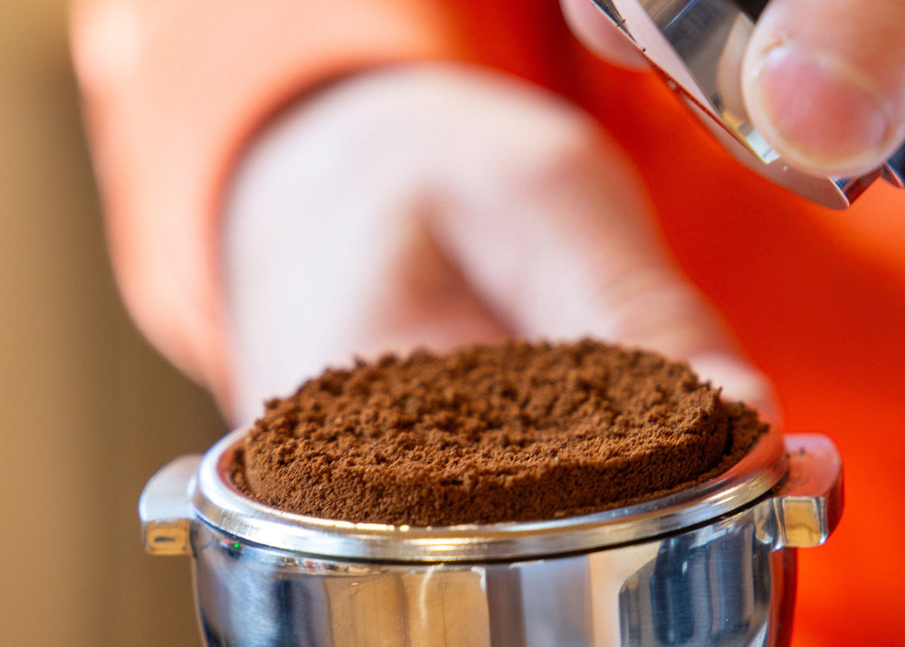 Hand tampt frisch gemahlenes Espressopulver im Siebträger beim Barista Kurs der Murnauer Kaffeerösterei, Kaffee-Akademy, Baristakurs Espresso & Latte Art