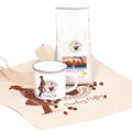 Geschenkset Cowboy Coffee frontal mit weißer Kaffeepackung, Emailletasse und bedruckter Baumwolltasche der Murnauer Kaffeerösterei, Bohnen auf dem Stoff