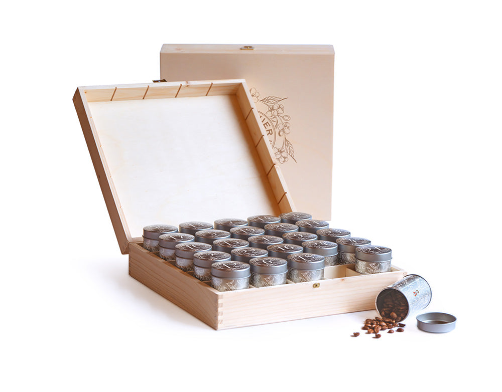 Geöffnete helle Holzbox mit 24 silbernen Kaffeeblechdosen des Kaffee-Adventskalenders 2026 der Murnauer Kaffeerösterei vor weißem Hintergrund