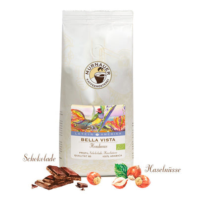 Weiße Kaffeepackung Bella Vista Honduras der Murnauer Kaffeeroesterei mit Schokolade und Haselnüssen davor