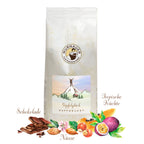 Weiße Kaffeepackung Gipfelglück Kaffeelust der Murnauer Kaffeerösterei, davor Schokolade, Nüsse und tropische Früchte als Aromen
