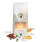 Weiße Kaffeepackung Best Cup 2 Pacha Mama der Murnauer Kaffeerösterei mit Schokoladenstücken, Honig und Jasminblüten als Aromensymbole vor weißem Hintergrund, Kaffee aus Amerika Peru