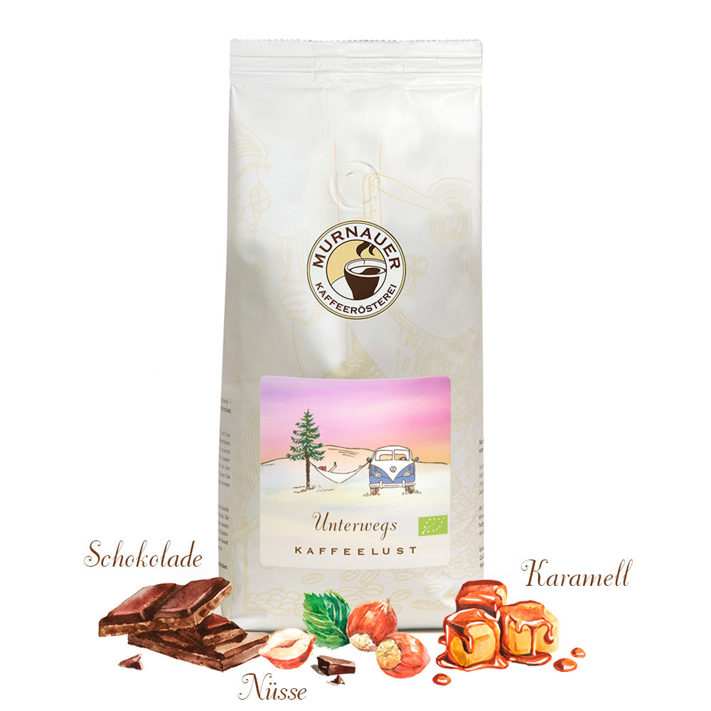 Weiße Kaffeepackung Unterwegs Kaffeelust der Murnauer Kaffeerösterei, davor Schokolade, Nüsse und Karamell als Aromen