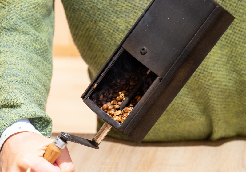 SCA-Trainer Michael Eckel im Kaffeegeheimnis Kurs prüft frisch gemahlene Kaffeebohnen im Auswurf des Handrösters 