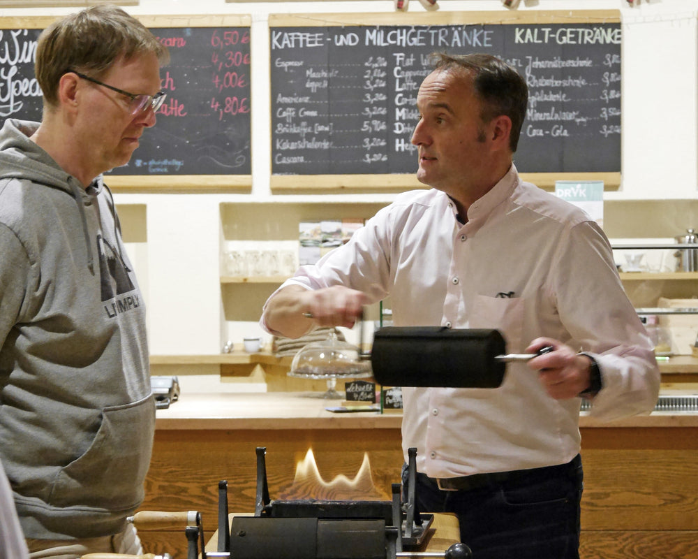 Kaffeerösten Kurs mit Inhaber Thomas Eckel an Handröstern der Kaffee Academy im Murnauer Kaffeehaus an Holztheke, erklärt den Röstprozess vor Teilnehmern