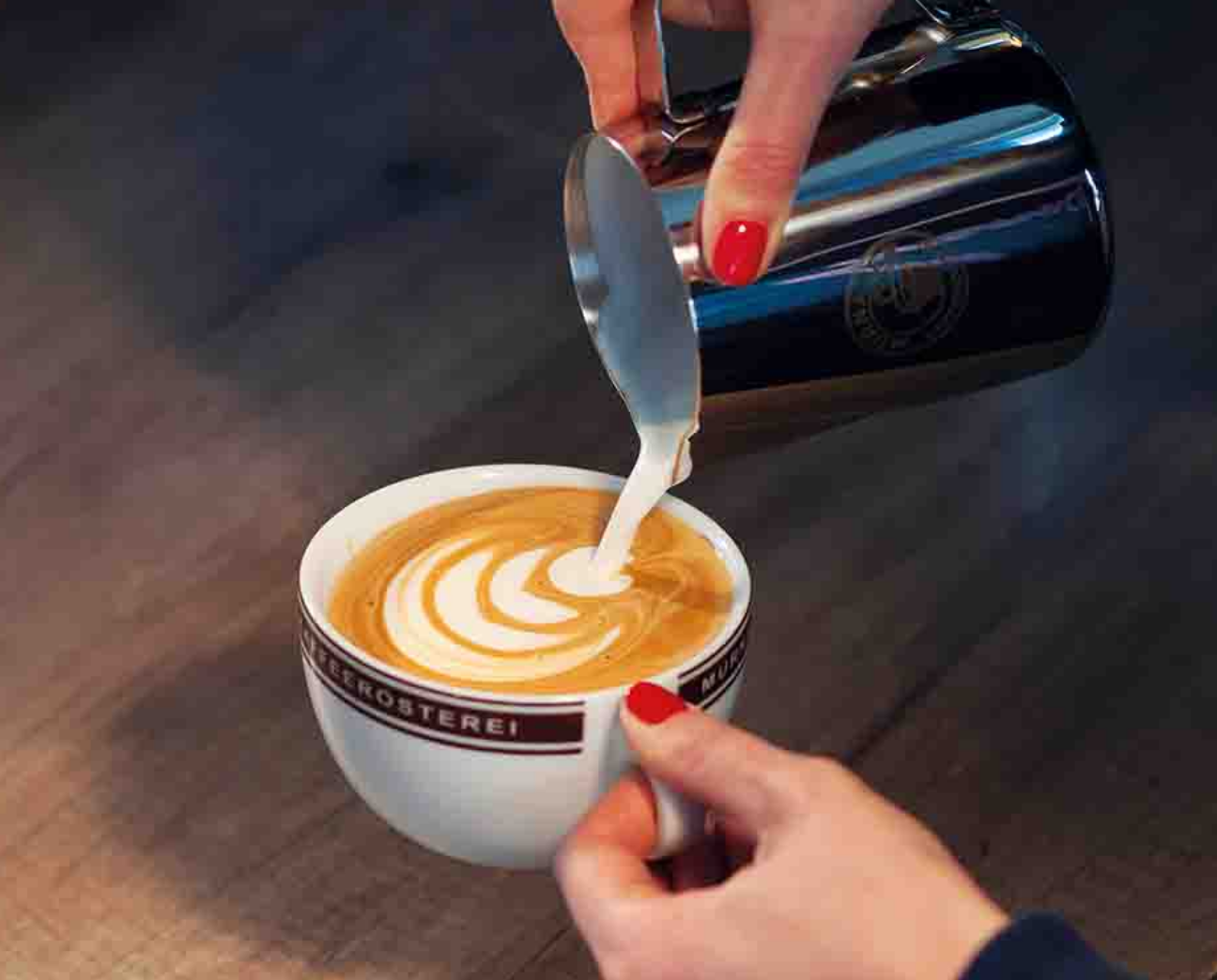 Barista gießt Milchschaum für Latte Art