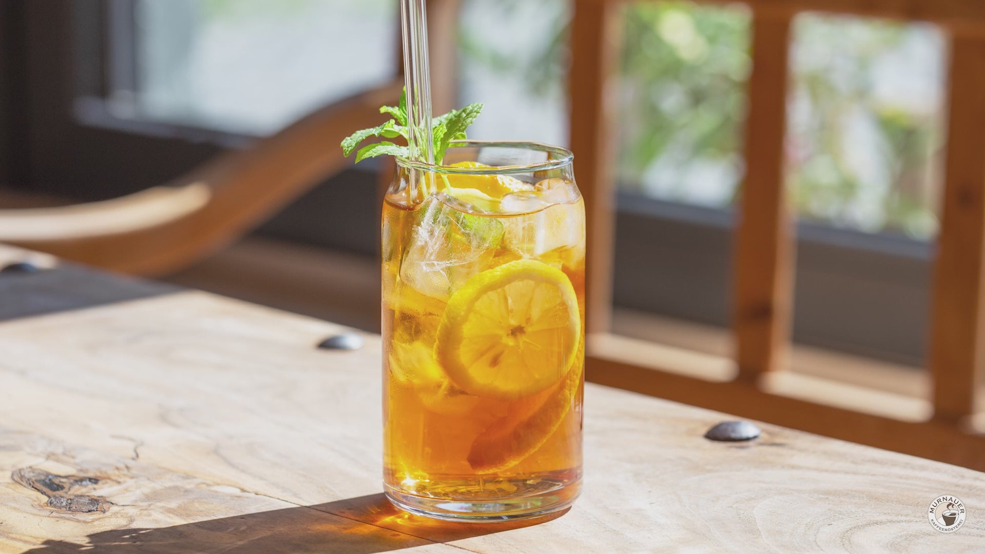 Video der Zubereitung von Cascara-Eistee im Glas mit Eiswürfeln, Zitronenscheibe, Minze und Glasstrohhalm als erfrischendes Sommergetränk, 
