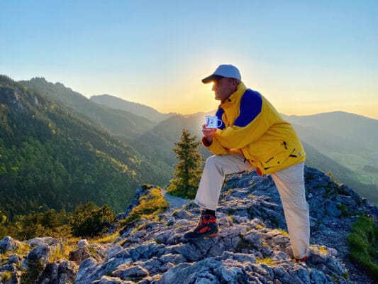 Herr in den Bergen hält seine Kaffeetasse in der Hand - Kaffee und Sport