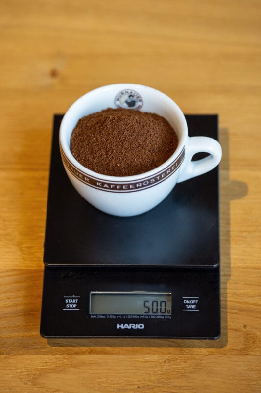 Murnauer Kaffeerösterei: Cold Brew Guide: Grob gemahlenes Kaffeepulver steht in einer Tasser auf einer Waage und wird gewogen