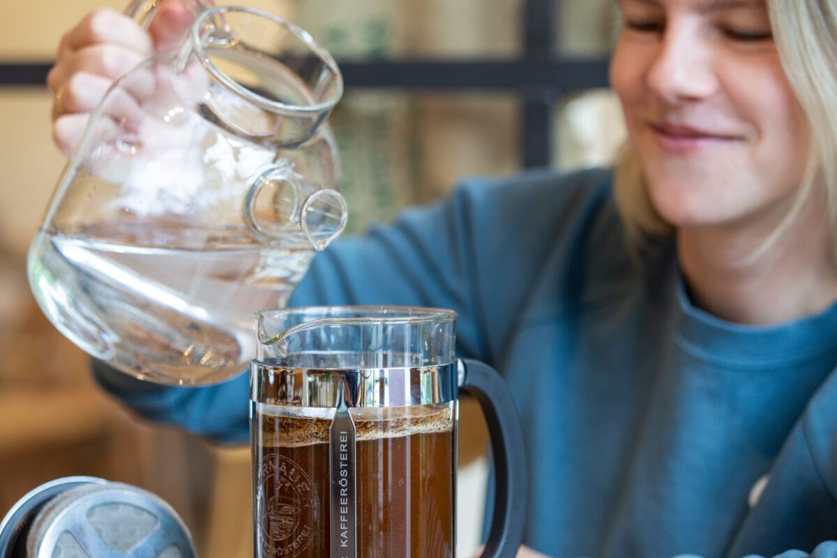 Frau bereits Cold Brew zu: In eine French Press wird kaltes Wasser eingegossen