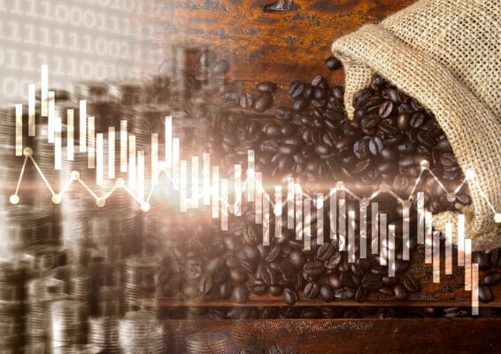 Kaffeebohnen auf Holztisch mit Preisdiagramm und Münzsymbolik im Hintergrund