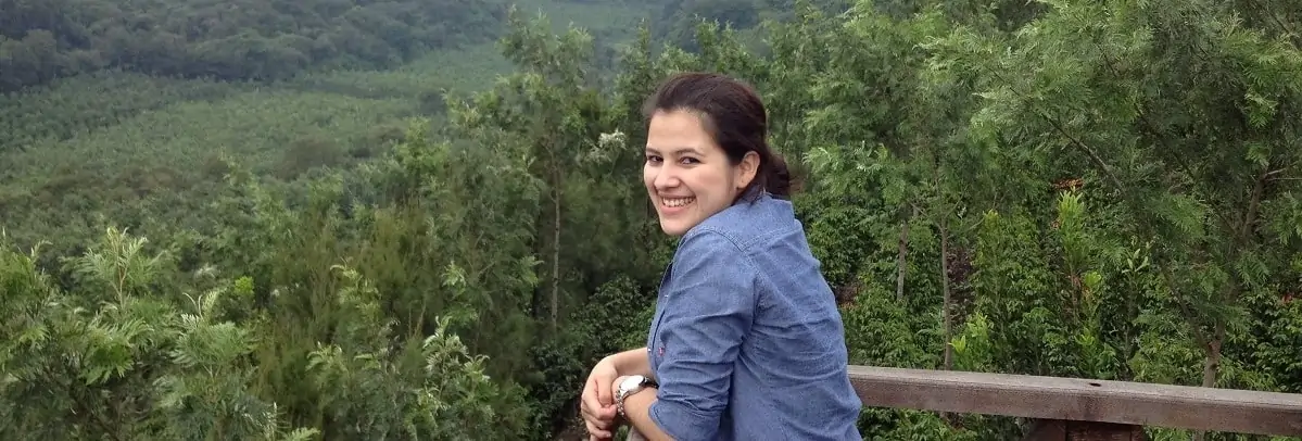 lachende Frau auf Balkon vor bewoelktem Regenwald vn Plantage San Sebastian